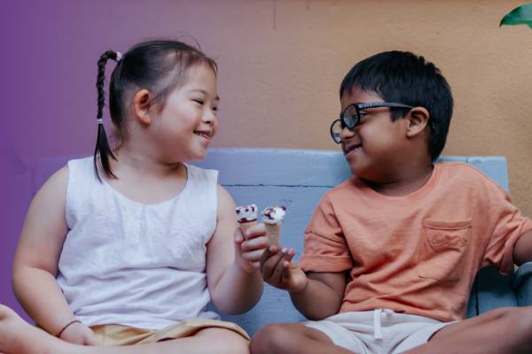 Two children looking at each other while they eat ice cream